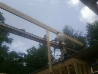 Carpenter setting a ridge beam over a new addition frame — Ice Dam Removal by Roofing Brothers in Harpersville