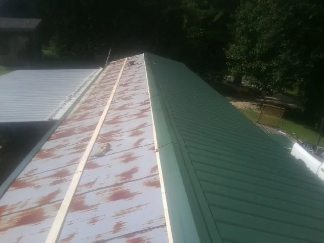 Old rusted panels beside newly installed green metal roofing — Wind Damage Roof Repair by Roofing Brothers in Harpersville