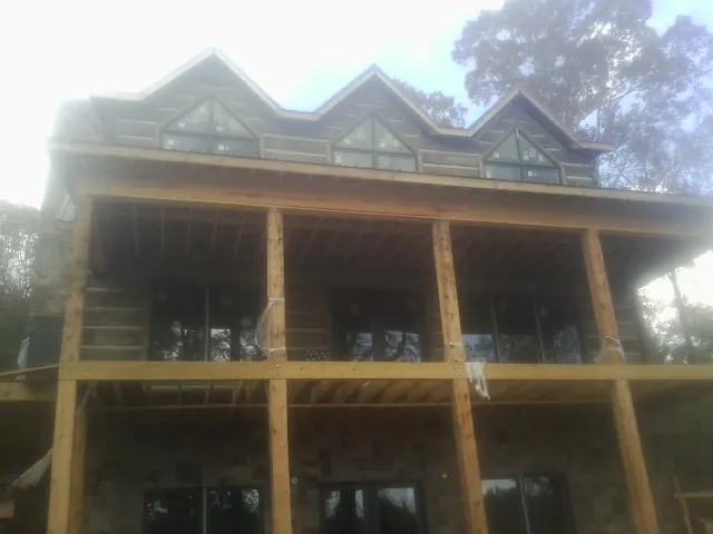 Dormers and porch framing on a large log home under construction — Roof Coating work by our crew in Harpersville