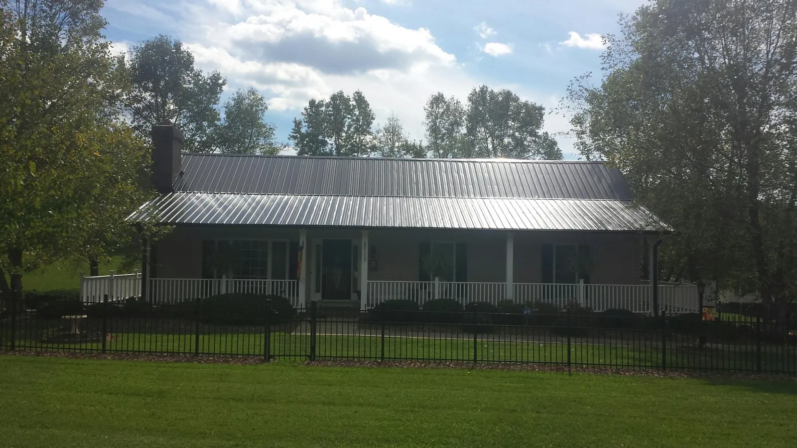 Gray metal roof on a brick ranch with a full width front porch — Gutter Guard Installation work by our crew in Harpersville