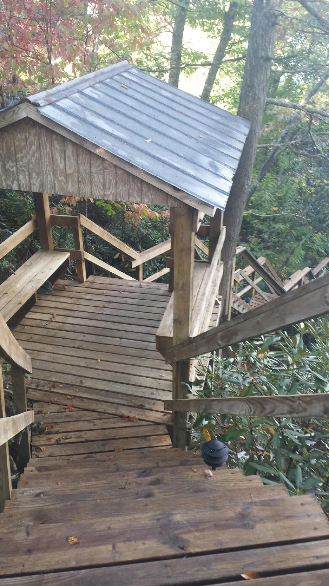 Metal roofed shelter over wooden steps on a wooded walkway — Skylight Repair & Installation work by our crew in Harpersville