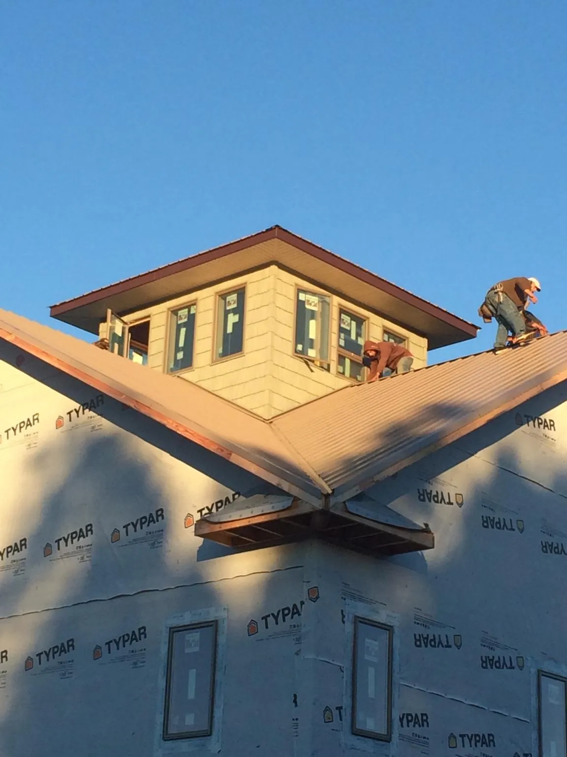 Roofers working around a rooftop cupola on a new metal roof at sunset — Roof Waterproofing in Harpersville by Roofing Brothers